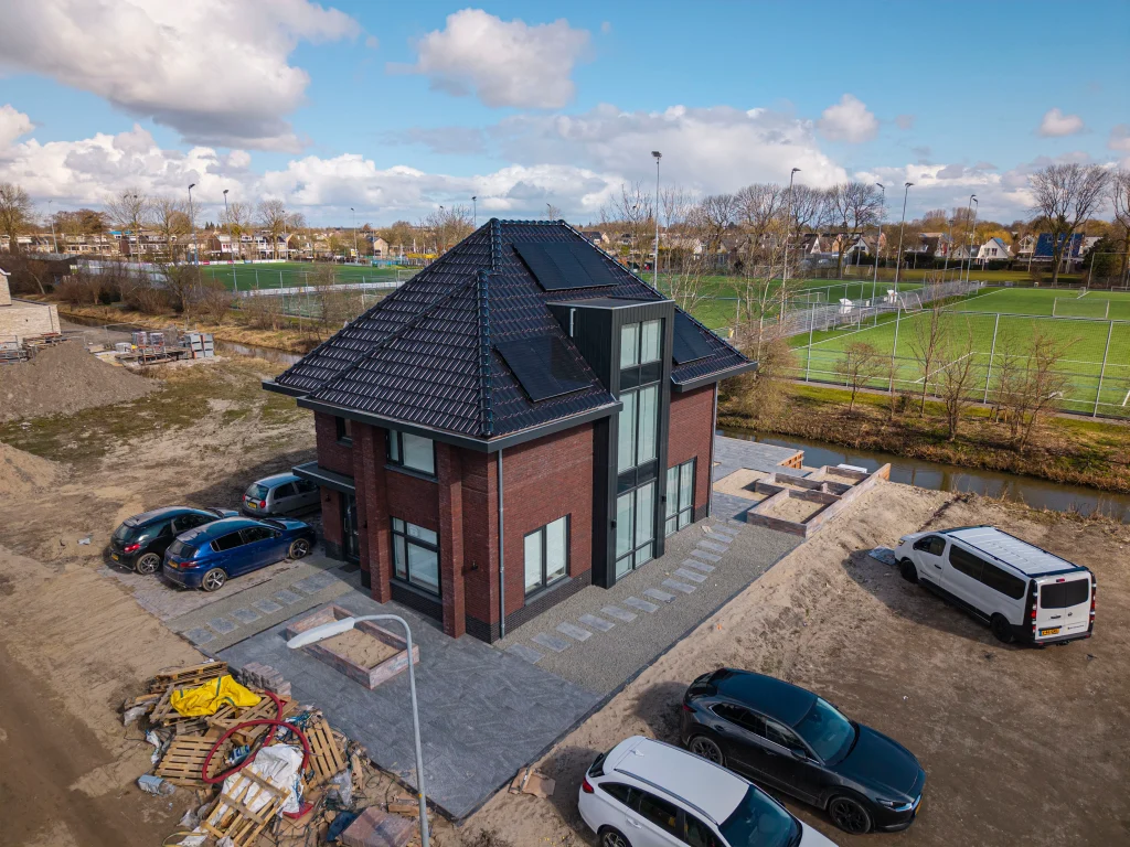 Moderne tuin met keramiek tegels en oprit met klinkers in Zwaag