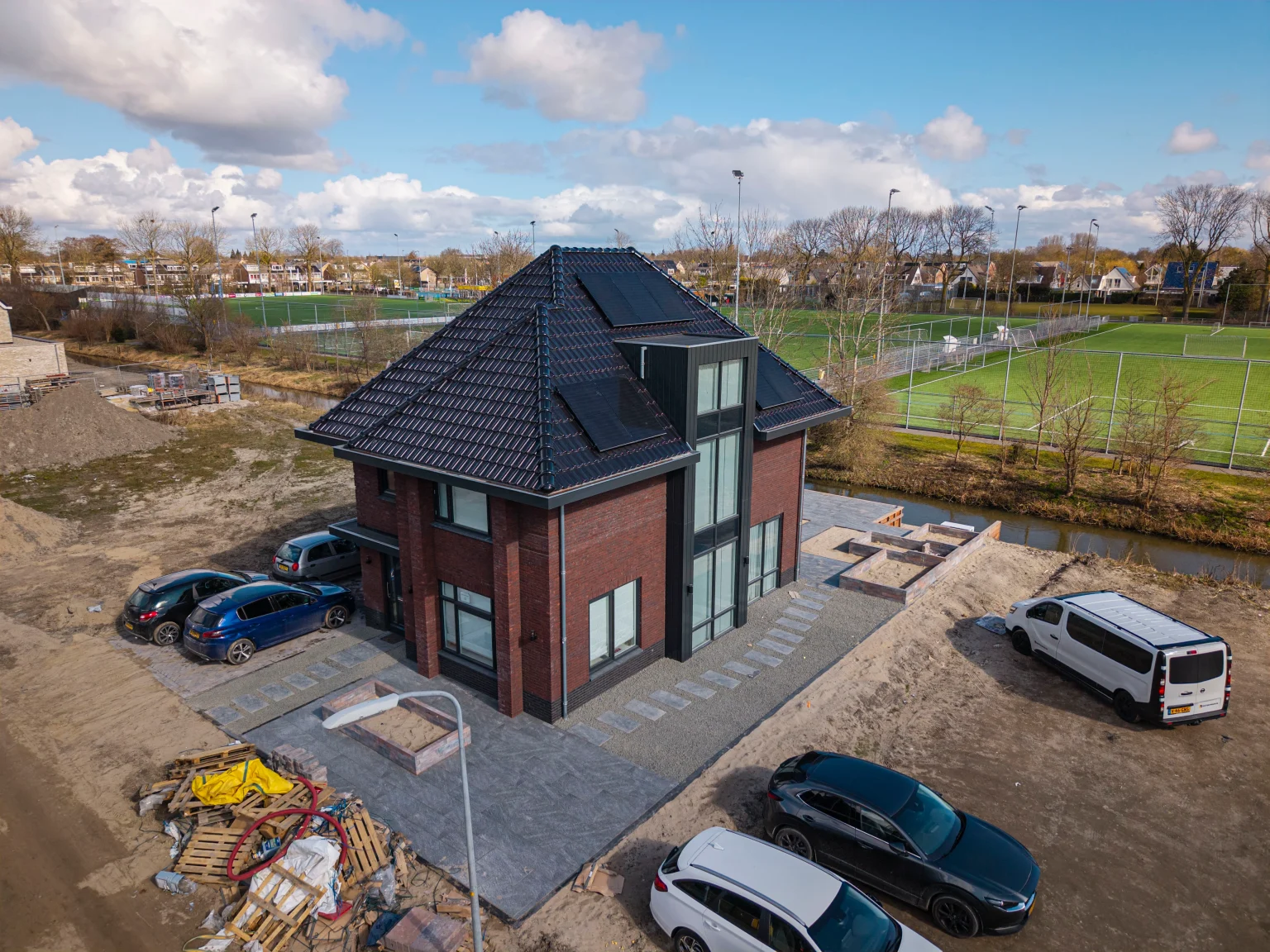 Moderne tuin met keramiek tegels en oprit met klinkers in Zwaag